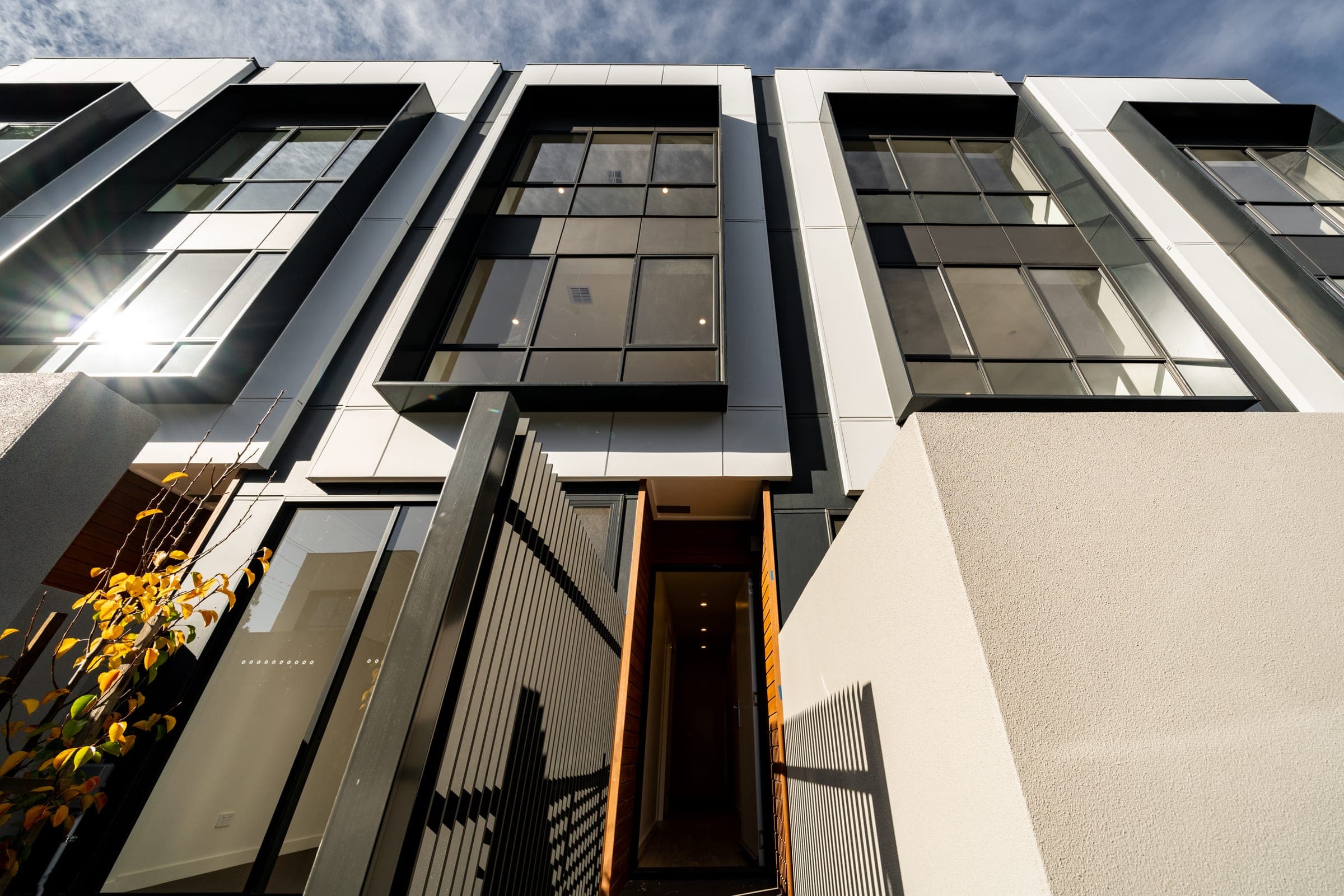 Contemporary three-storey townhouse facades with timber-lined entry